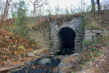vintage ancient bridge tunnel canal drainage ditch river waterway stone water landscape - obrazy, fototapety, plakaty