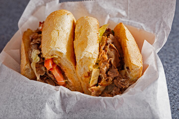 Cheesesteak sub sandwich cut in half in parchment paper