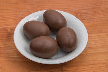 ceramic plate with four easter chocolate eggs, isolated on wood