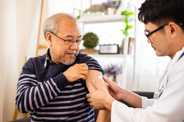Safe vaccination for old people. Elder man in medical  getting flu or Covid-19 vaccine sitting on...