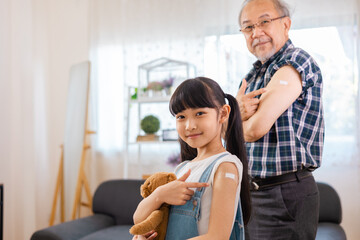 Senior man after vaccination and  granddaughter at home. Virus protection. COVID-2019.Vaccination in the shoulder of child patient  at home.