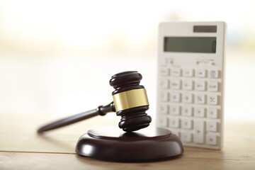 Wooden judge's gavel and calculator on table - obrazy, fototapety, plakaty