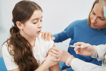 Obraz na płótnie Canvas Little girl getting injection in pediatric clinic