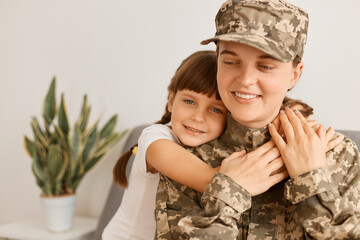 Horizontal shot of extremely happy satisfied woman wearing camouflage uniform and cap posing with...