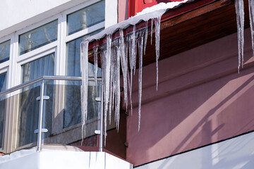 Long transparent icicles on the roof on a spring sunny day