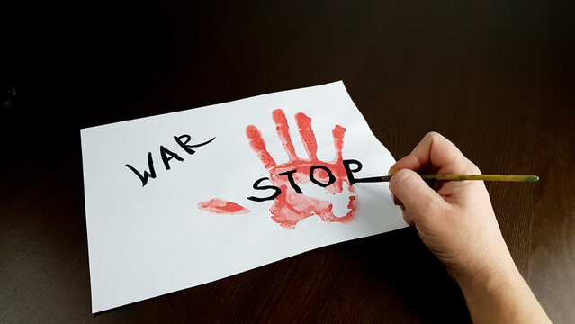 a person writes stop war on white paper. bloody hand palm print