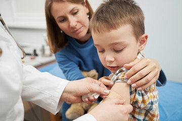 Doctor placing medical plaster on child arm after vaccination - obrazy, fototapety, plakaty