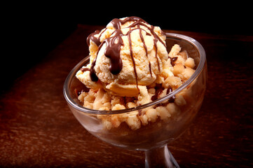 ice cream cup dessert with apple pie and chocolate sauce close-up on wooden table