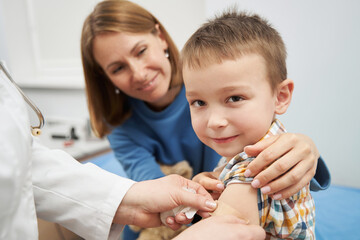 Pediatrician placing medical plaster on child arm after vaccination