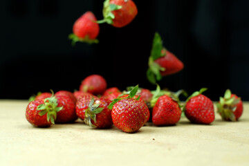 Fresh strawberries floating above the table against a studio black background	