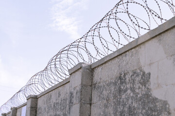 Prison or military zone fenced with a big wall with barbed wire on top 