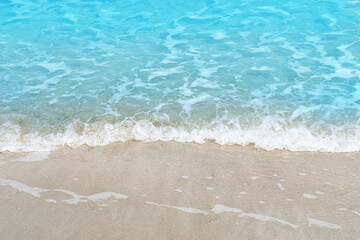 Soft blue ocean wave on sandy beach for texture copy space and background