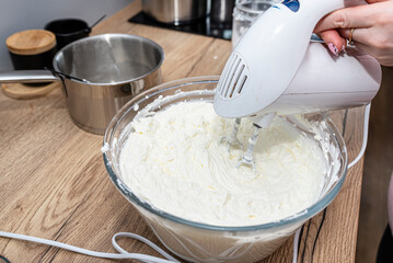 Mixing the curd and whipped cream into the cheesecake with a hand mixer with a whisk.