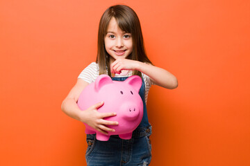Cute girl saving money on piggy bank