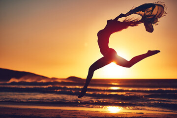 The best freedom is being yourself. Silhouette of an energetic woman jumping on the beach at sunset.