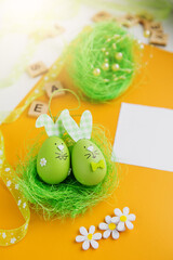 Easter composition. Easter eggs, decorative bunnies and decorations on a yellow background. Flat lay, top view, copy space