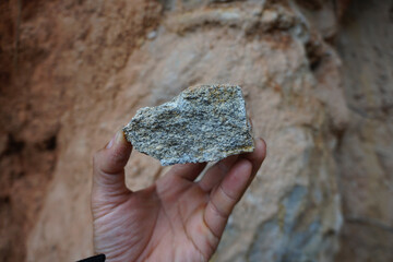 A geologist's hand is holding a piece of granite rock.