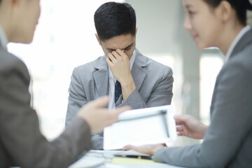 Frustrated businessman with head in hands in meeting