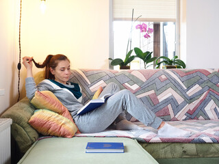 woman reading a book sitting on the couch in home
