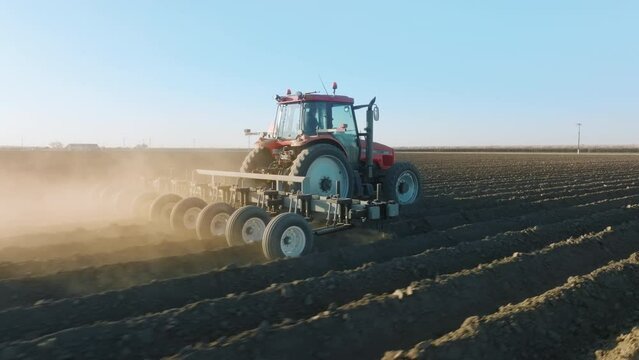 Drone footage of a tractor turning the soil before planting. Agricultural machine with heavy blades cuts a furrow for sowing seeds. High quality 4k footage