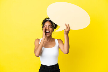 Young african american woman isolated on yellow background holding an empty speech bubble and shouting