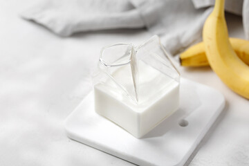 Fototapeta na wymiar Milk in glass jar with banana. Milk in the modern milk jug. Sunshine.
