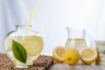Heart-shaped pitcher with lemonade and cubes, a slice of lemon and a leaf, in the background...