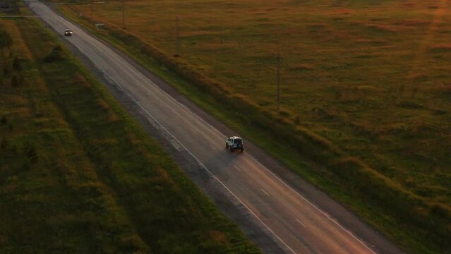 Aerial view of a car driving on the road at sunset