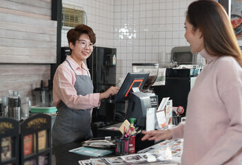 cashier staff receive customer orders from a waitress at counter in coffee shop.