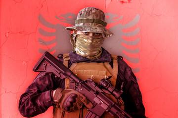 Angry albanian soldier armed with a rifle with albania flag as background behind - obrazy, fototapety, plakaty