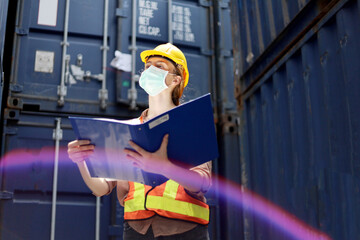 Young Engineers standing in the shipping yard tracking the cargo inventory and checking container...