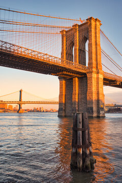 Brooklyn Bridge during sunset in winter. Famous Brooklyn Bridge in orange light from the setting sun. Wonderful clear and crisp picture of New York's bridges on a cold winter day.  