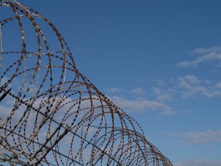 Barbed steel razor wire against sky background. Barrier.