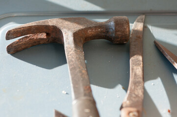 old rusty hammer and gardening knife on a plastic surface