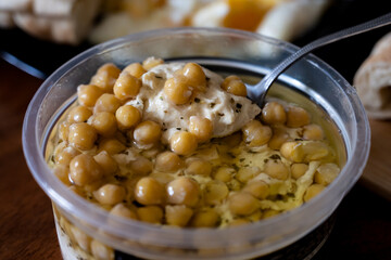 Home made hummus bowl, decorated with boiled chickpeas, herbs, pita and olive oil over a rustic metal background.