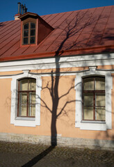 Old building with tree shadow at blue sky background.
