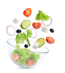 Greek salad ingredients fall into a transparent glass salad bowl