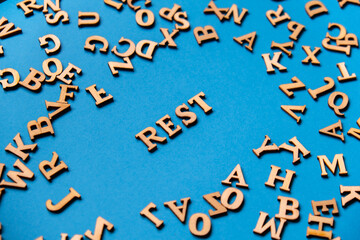 Word REST made out of wooden letters on bright blue background. Motivational Words Quotes Concept.