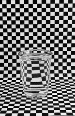glass with water refracting on the black and white checkered background