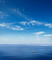 Sailboat sails on open sea with blue sky