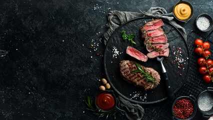Grilled rib eye steak on a fork, herbs and spices. Top view with copy space for text. Top view with...