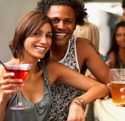Closeup of a smiling young couple in a bar. A cropped portrait of happy young people having drinks at a bar.