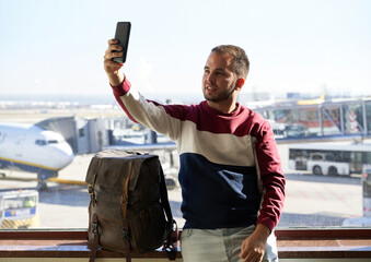 young man smiles to take a selfie at the airport