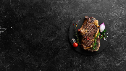 Juicy grilled steak on the bone cooked on the grill. Barbecue. On a black stone background.