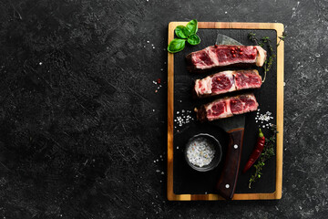 Veal steak on the knife. Grill steak. Free space for your text. On a black stone background.
