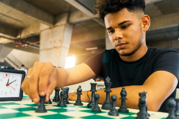 Latin young man practicing chess techniques in a basement. Concept of intellectual development in the millennial youth of Nicaragua, Central America and South America. - obrazy, fototapety, plakaty
