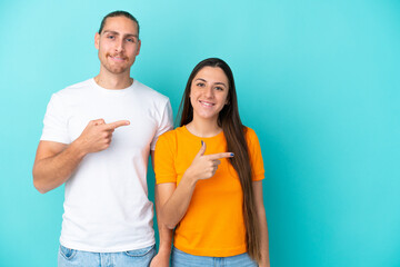 Fototapeta premium Young caucasian couple isolated on blue background pointing finger to the side and presenting a product