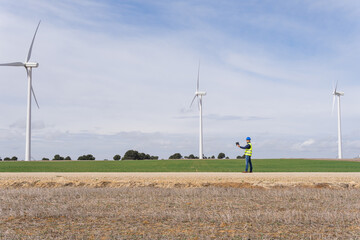 Fototapeta na wymiar Wind farm with electric generators in operation with an industrial engineer checking the operation of the installations from his digital device. Renewable energy concept.