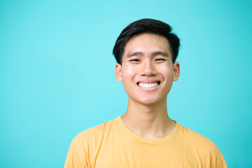 Close up portrait of young smiling handsome guy in yellow t-shirt isolated background.