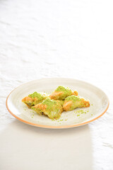 Pistachio baklava on a white wooden background. Baklava on a marble floor. Turkish baklava with pistachio, baklava slice